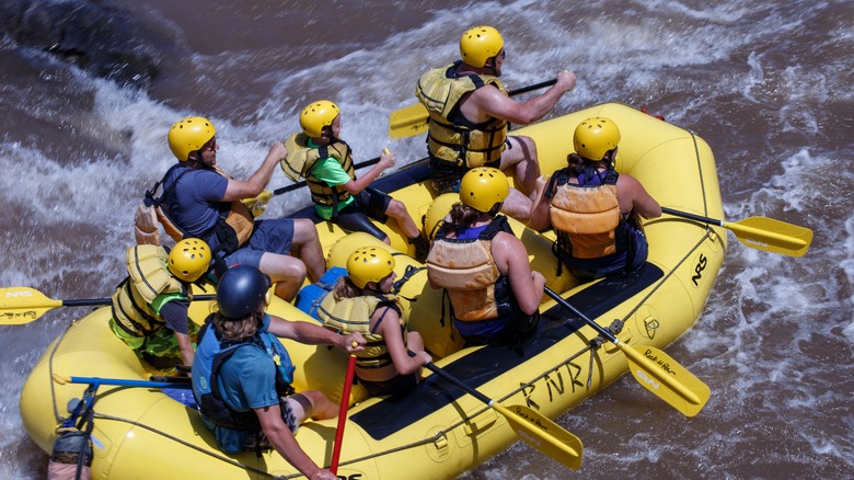 Eight people whitewater rafting on a yellow raft