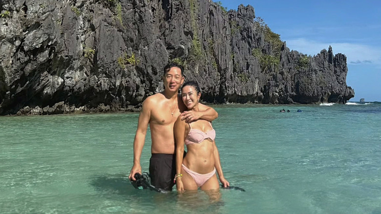 A couple enjoying the sea, in front of a cliff face, at Palawan.