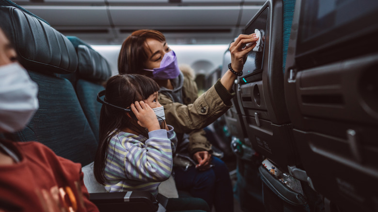 Mom cleans inflight tv screen for child