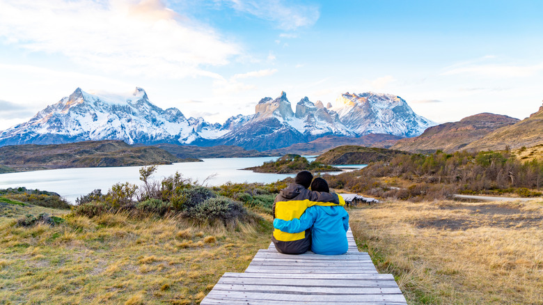 Couple sitting on boardwalk overlooking Patagonia mountains in Chile