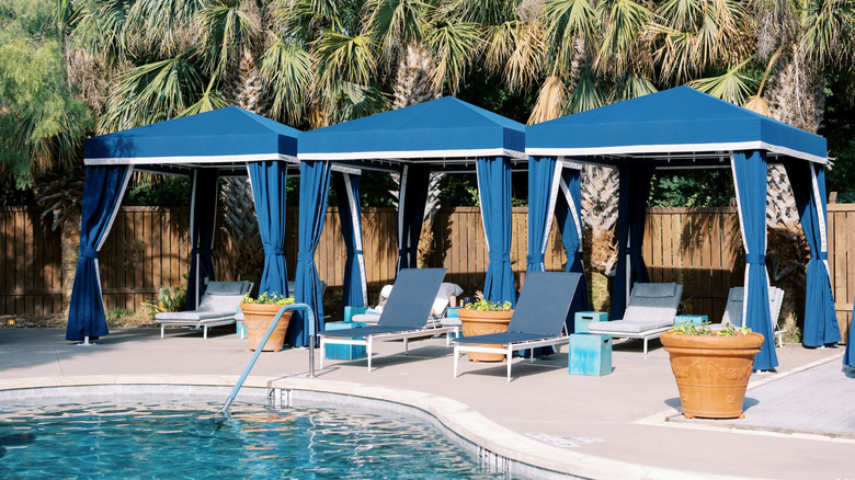 Three blue awnings above lounge chairs by a pool