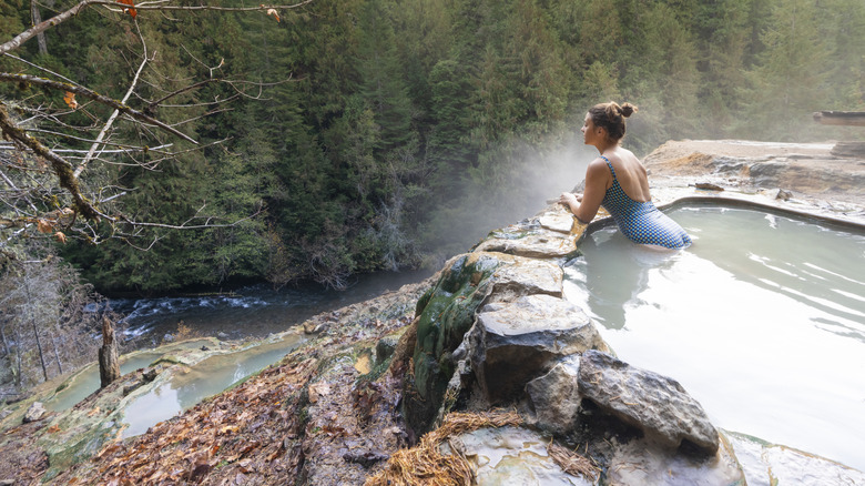 Woman with blue swimsuit relaxing in a hot pool in autumn, Umpqua Hot Springs, Douglas county, Oregon, United States.