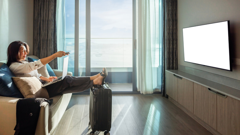 A woman turning the TV on in her hotel room