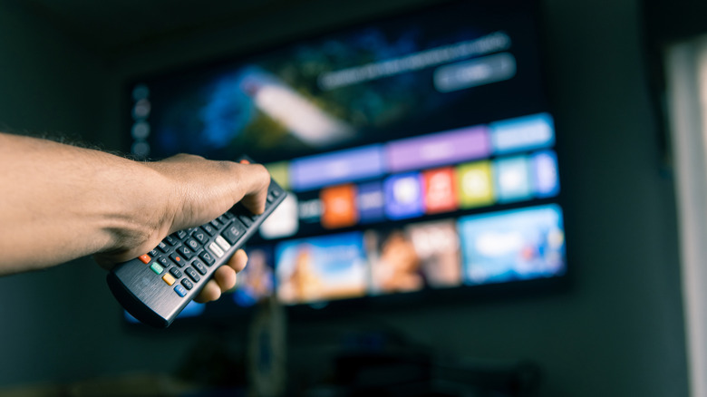 A person changing pointing a remote at the TV with a streaming service connected
