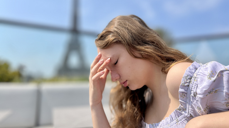 A woman with a headache, Eiffel Tower behind her