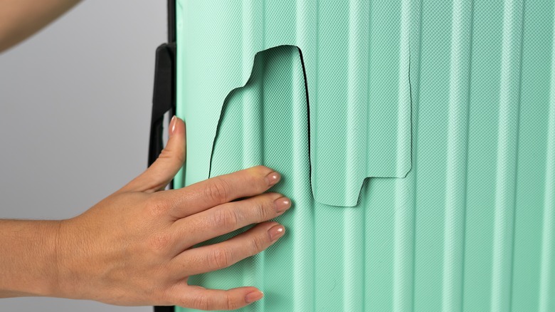 Woman examines a broken suitcase