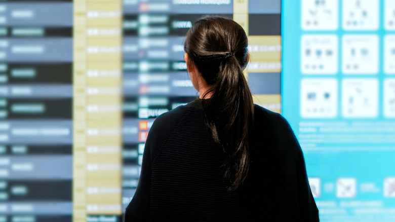 Traveler looking at departure board at airport