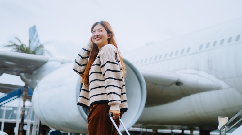 Excited traveler approaching the plane with her luggage