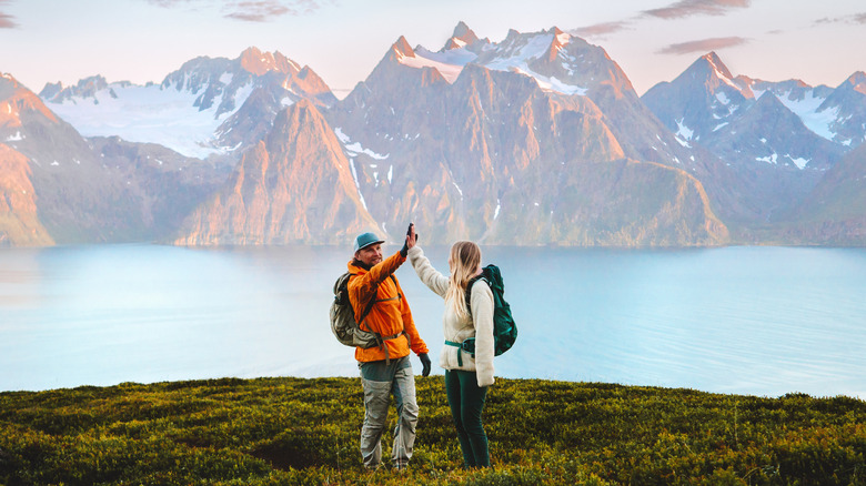 A couple high-fives near a mountain landscape
