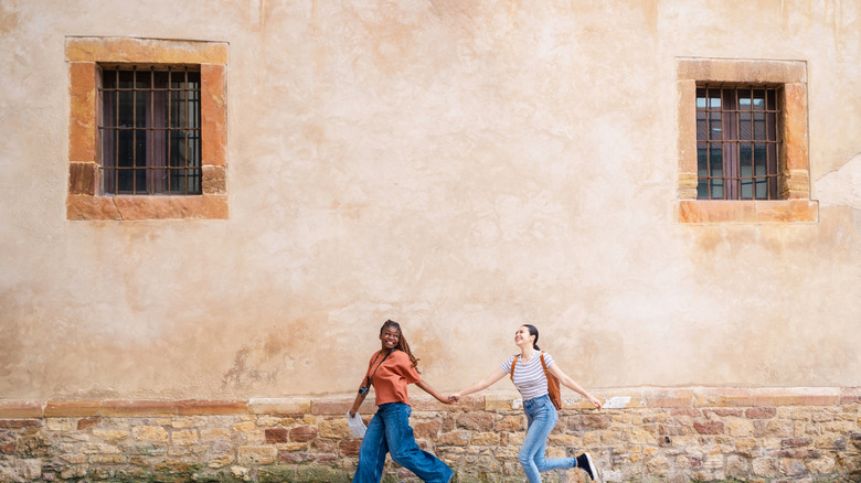 Two female travelers walking through cobblestone street
