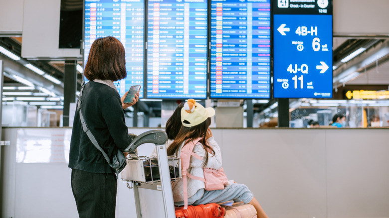Traveler with children checking airport departure board