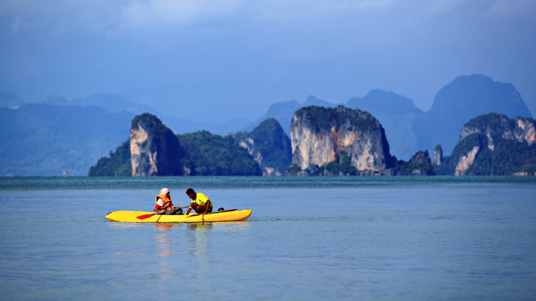 A couple on a yellow kayak with karst limestone islands in the backdrop