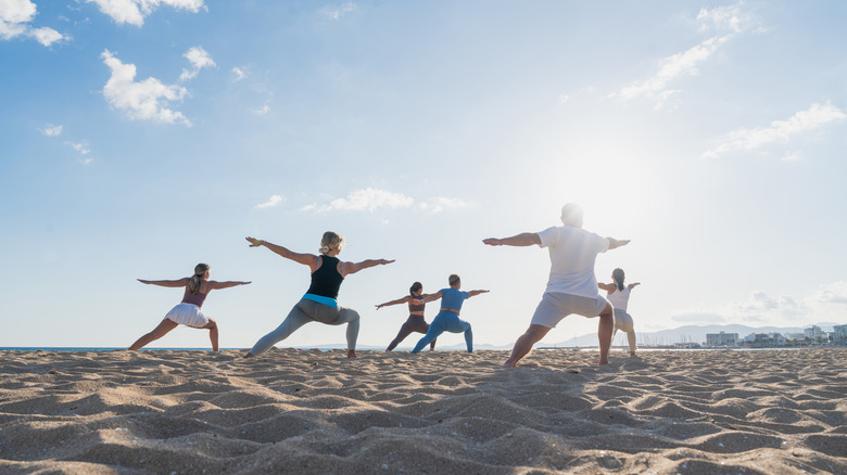 A group of people doing yoga on the beach on a sunny day.