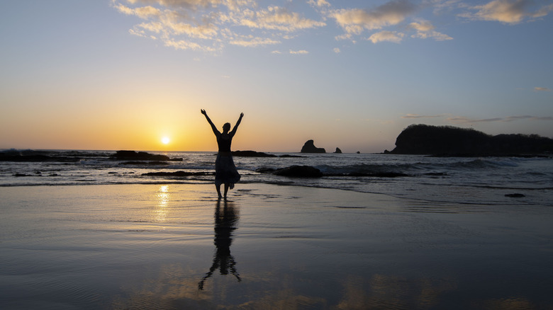 Woman on Playa Maderas at sunset with her reflection in the ocean