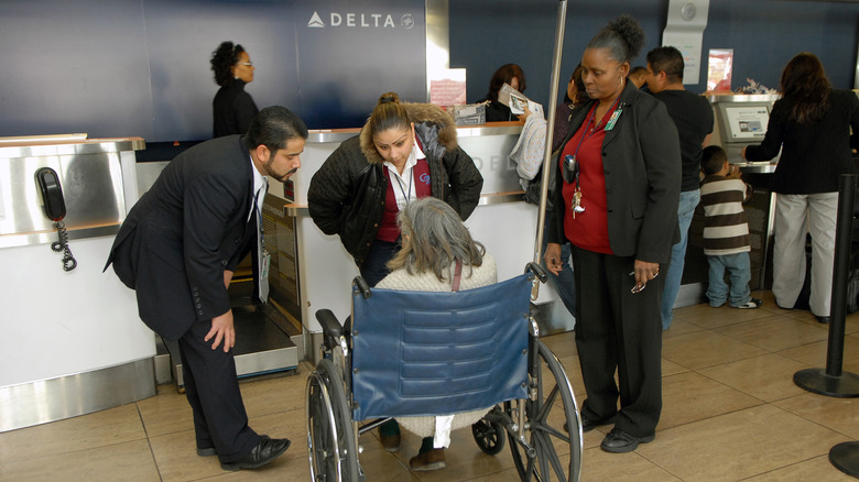 Delta employees speak to an elderly woman in a wheelchair