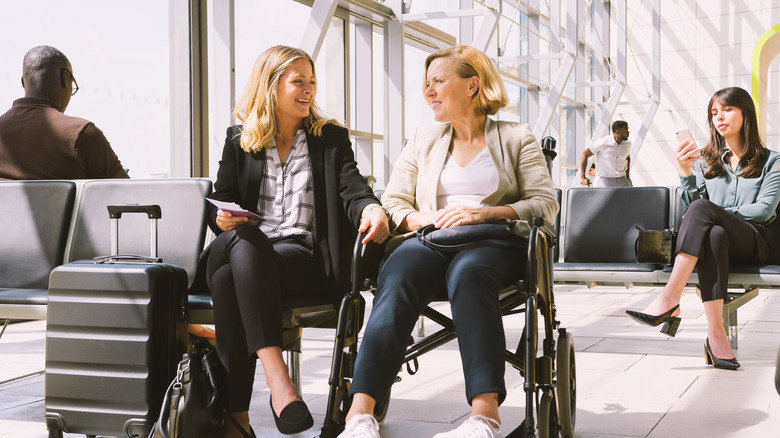 a passenger in a wheelchair speaks to their friend at the airport