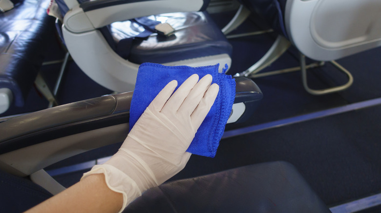 Gloved hand cleaning an airline seat