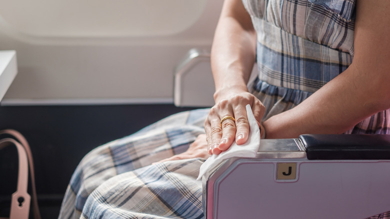 A woman cleaning an armrest on a plane