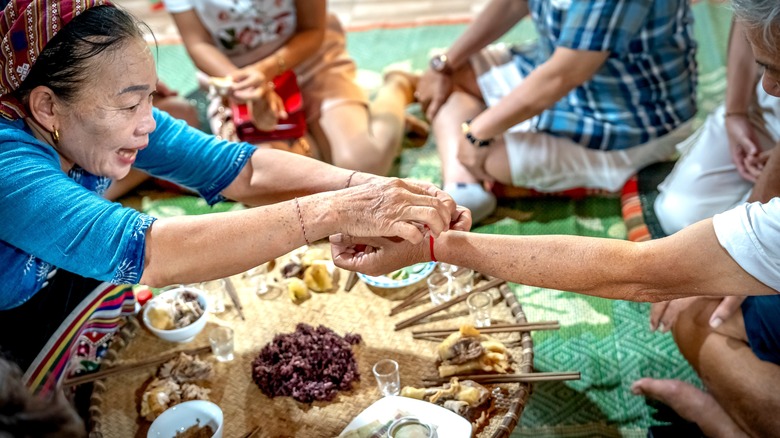 A wrist-tying ceremony at a homestay in Viet Nam with food