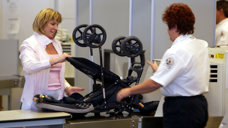 A woman prepares a stroller for X-ray screening with the help of a TSA agent.