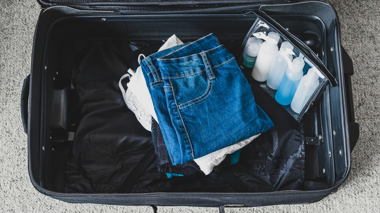 Suitcase filled with clothing and and liquids in a clear bag