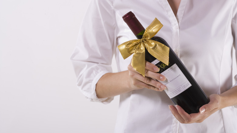 Person holding a bottle of wine as a gift