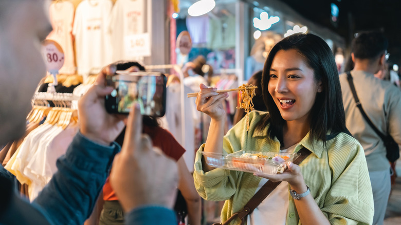 A woman wearing a cross-body bag in a night market