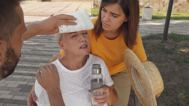 People helping woman with heat stroke