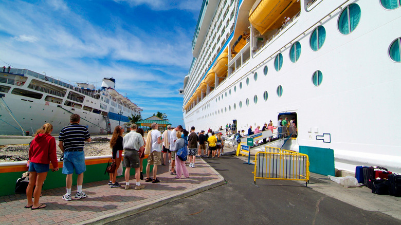 Travelers lining up to board a cruise ship on a dock