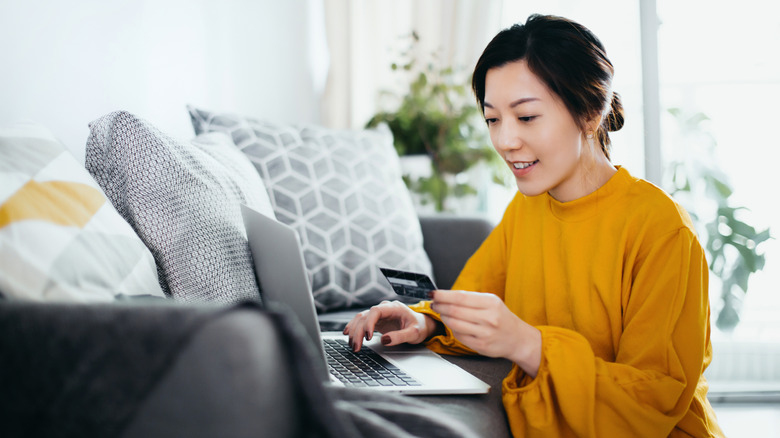 Person on computer holding a credit card