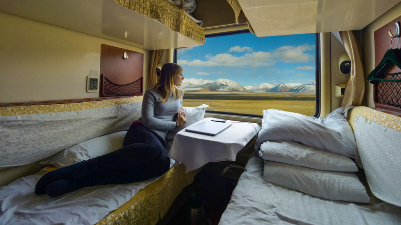 A woman laying on the bed of a sleeper train in Tibet