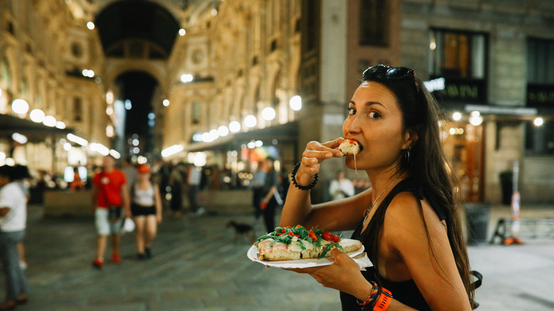 A woman eating pizza in Milan