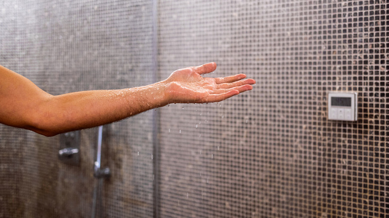 A hand testing shower water to make sure its warm