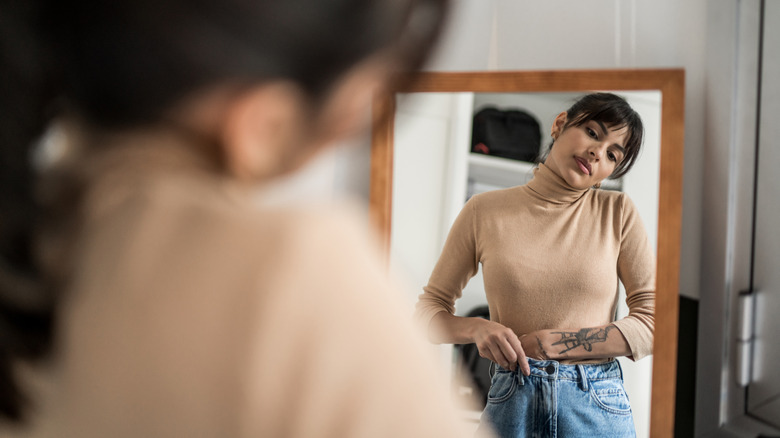Young woman trying on outfits at home