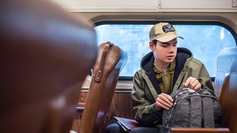 Train passenger zipping up their backpack