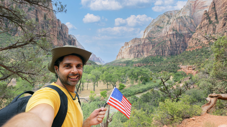 Man holding an American flag and taking a selfie in Zion National Park