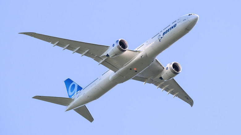 A Boeing aircraft flying in a bright blue sky, photographed from below