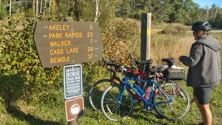 Bike rider looking at sign on trail