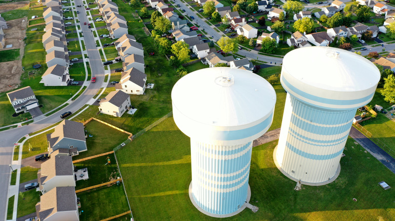 Aerial view of two white water towers overlooking a grassy suburban neighborhood