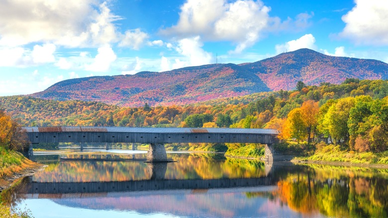 The historic Cornish-Windsor covered bridge crosses the Connecticut River in the Vermont mountains in fall
