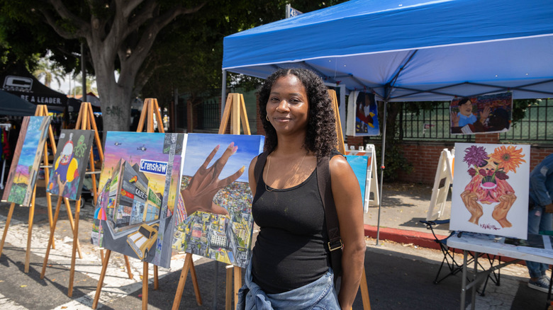 Artist standing in front of her art at a festival in Leimart Park