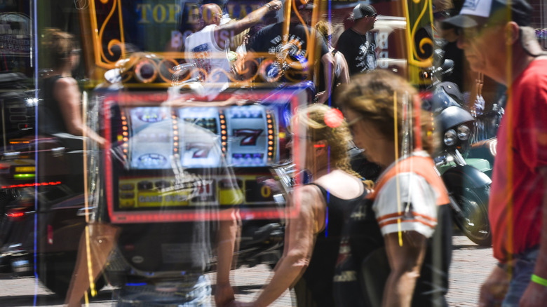 Travelers in Deadwood, South Dakota walk past casinos with vibrant slot machines