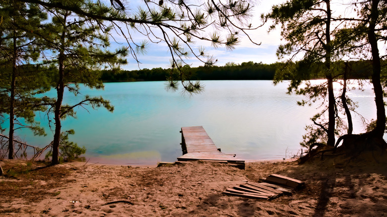 Blue Hole body of water with small dock in Hammonton, New Jersey during the day with trees in the distance.