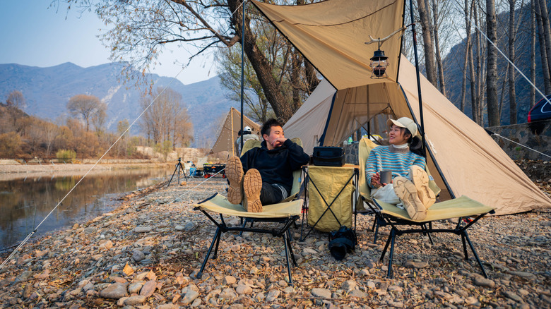 Young couple outside relaxing by their tent