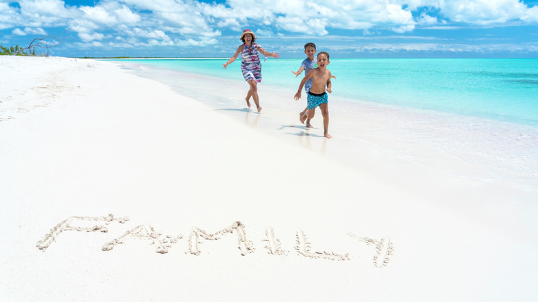 Woman chasing her sons on a white sandy beach