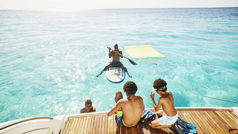 Brothers ready to swim in the Caribbean as father paddleboards nearby