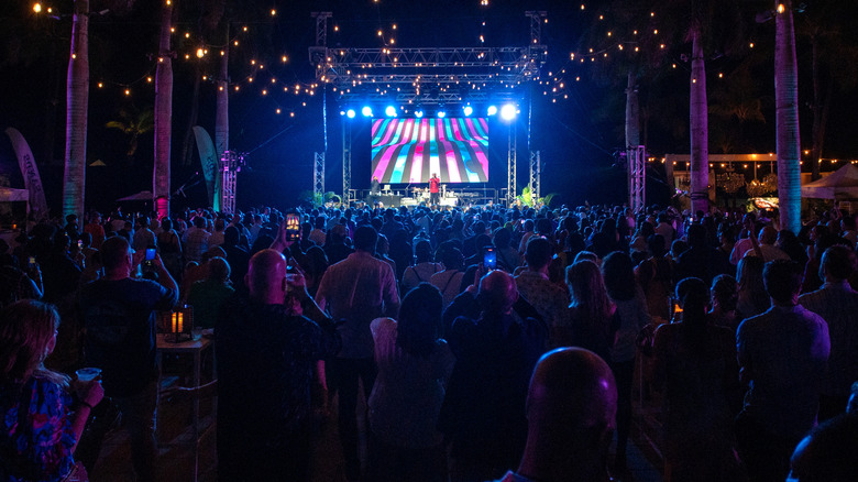 A wide view of a large crowd with many attendees holding beverages and enjoying a musical event at the Nassau Paradise Island Wine & Food Festival, in Nassau, Bahamas