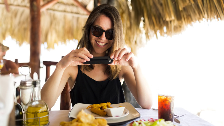 A woman taking a photo of her beachside food