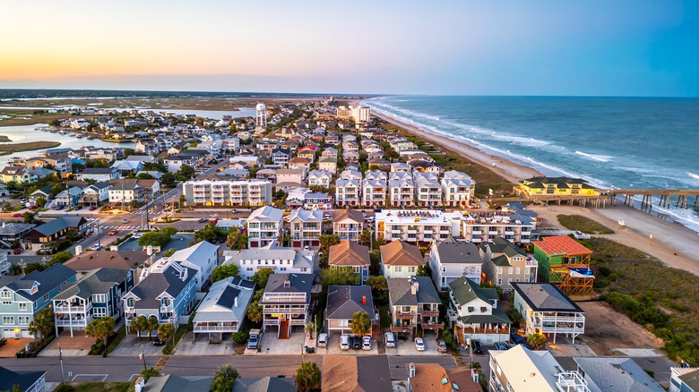 Aerial view of Wrightsville Beach at sunset, with colorful beachfront houses and a long pier