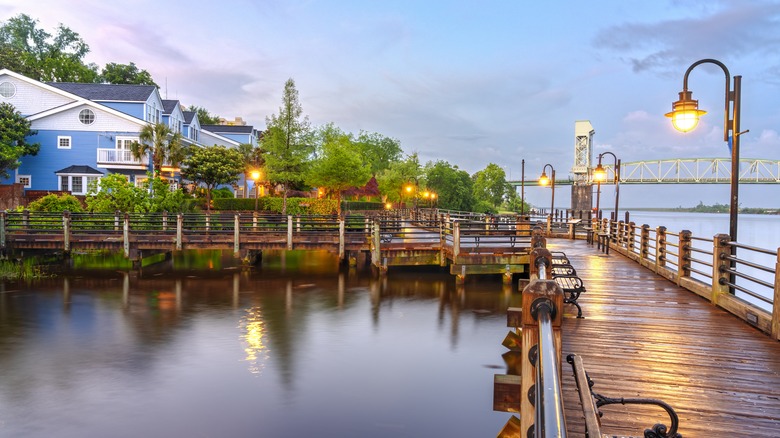 Riverfront with with wooden boardwalk lit by streetlamps at sunset, Wilmington, NC